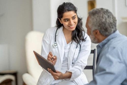 A nurse shows a patient a treatment plan on a clipboard.