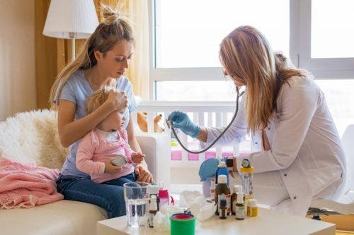 A nurse practitioner examines a young child with her mother.