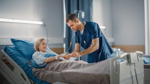 A nurse connects a heart rate monitor to a patient in a hospital bed.