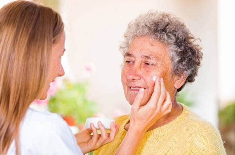 A nurse applies medication cream on an elderly patient.