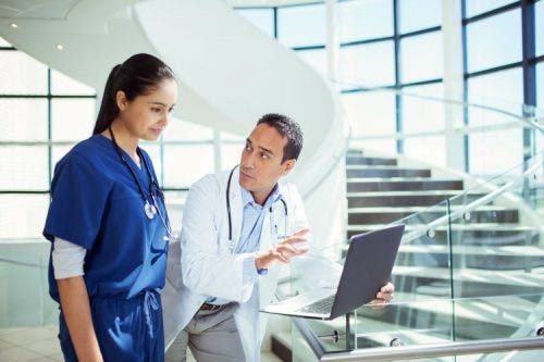 A doctor and nurse review patient information on a laptop.