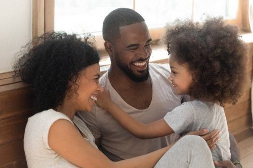 Smiling parents on the floor with a happy child.