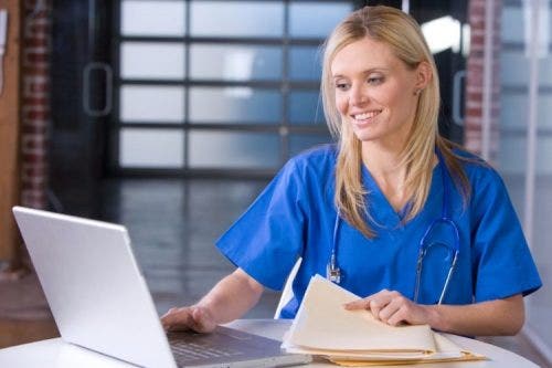 a female nurse sitting at a desk while using a laptop