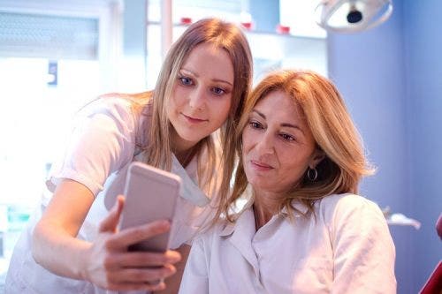 Young registered nurse shows a social media account to her charge nurse.
