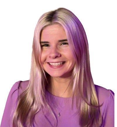Smiling headshot of Kelly, a woman with long blonde hair, wearing a purple top and small pendant necklace.