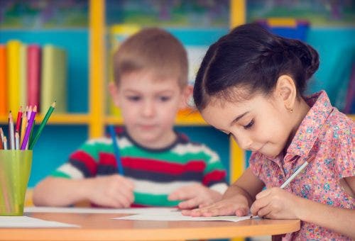 Two children sitting at a desk and writing.