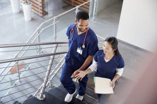 Two nurses walk up a stairwell discussing their patients.