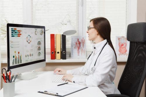 A nurse practitioner reviews nursing informatics data on her computer.