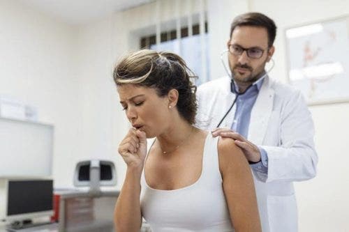 A patient with respiratory problems coughs while being examined by a nurse practitioner in a medical office.