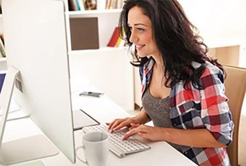 Online graduate student working on computer at desk.