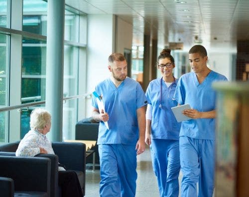 A group of nurses walk together down a hospital hallway.