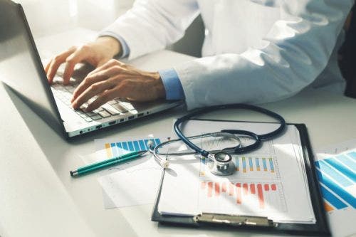 A biostatistician works on a computer while sitting at a desk in a health care setting.
