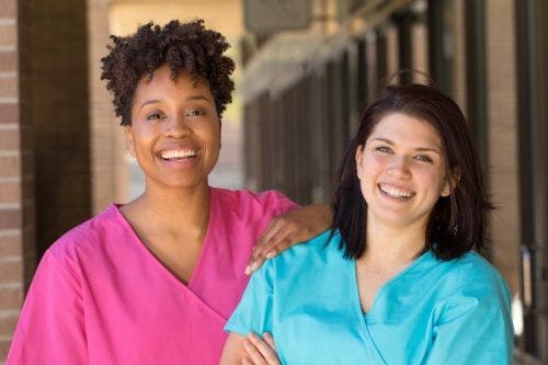 Two smiling nurses enjoy a break outside.