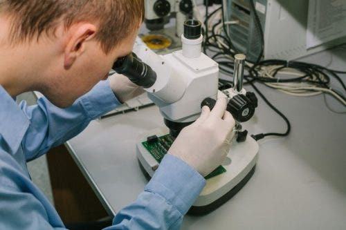 A forensic nurse looks through a microscope.