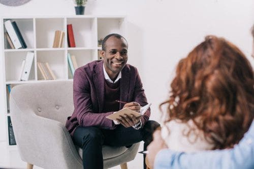 A psychotherapist discusses issues with a patient while sitting in his chair.