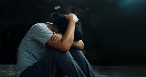 Someone with PTSD puts their hand on their head while sitting down.