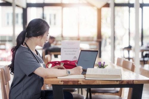 A nurse sits at a desk and takes notes