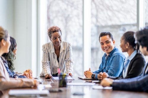 A social work supervisor leads a team meeting in a conference room.