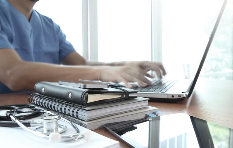 Nurse leader sitting at a desk and typing on a computer.