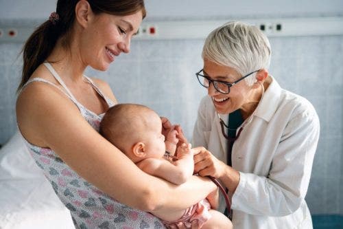 A nurse practitioner examines a baby being held by its mother.