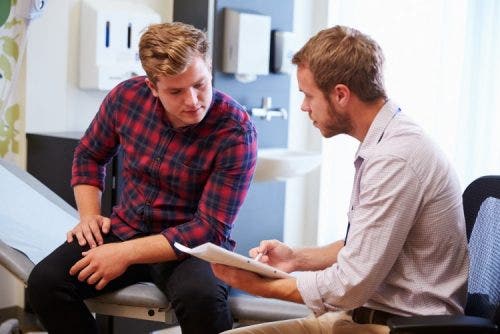 A nurse practitioner speaks with a patient in an exam room.