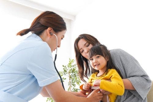 A nurse uses a stethoscope up to a child.