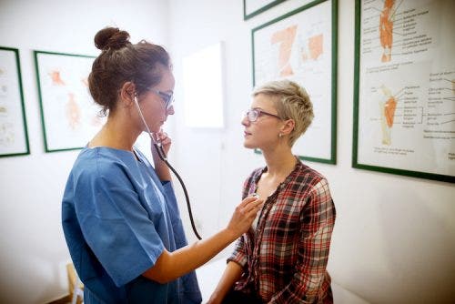 Nurse practitioner examining a patient with a stethoscope in a medical facility.