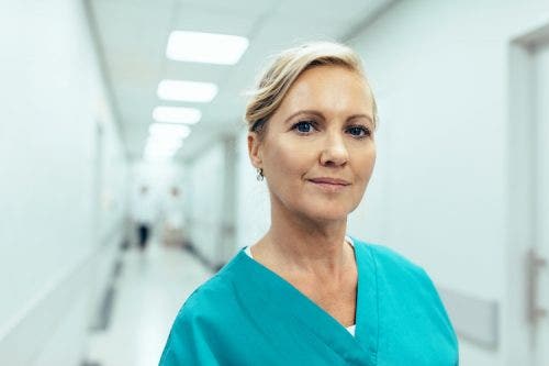 DNP poses in her scrubs in a hospital hallway.