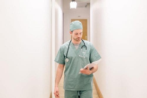 Nurse practitioner looking at notes while walking down a hallway