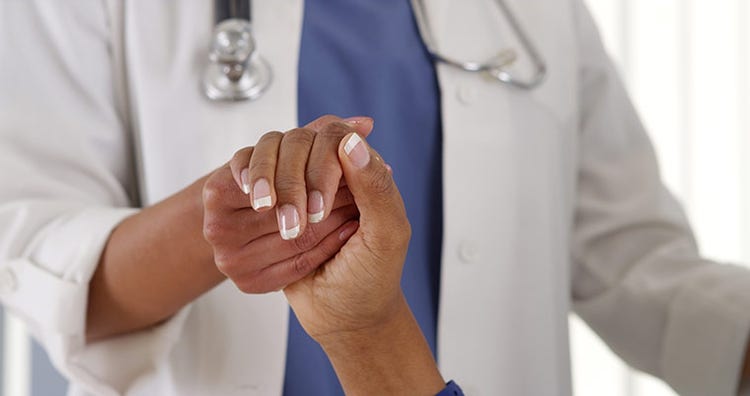 A nurse holds hands with a patient.